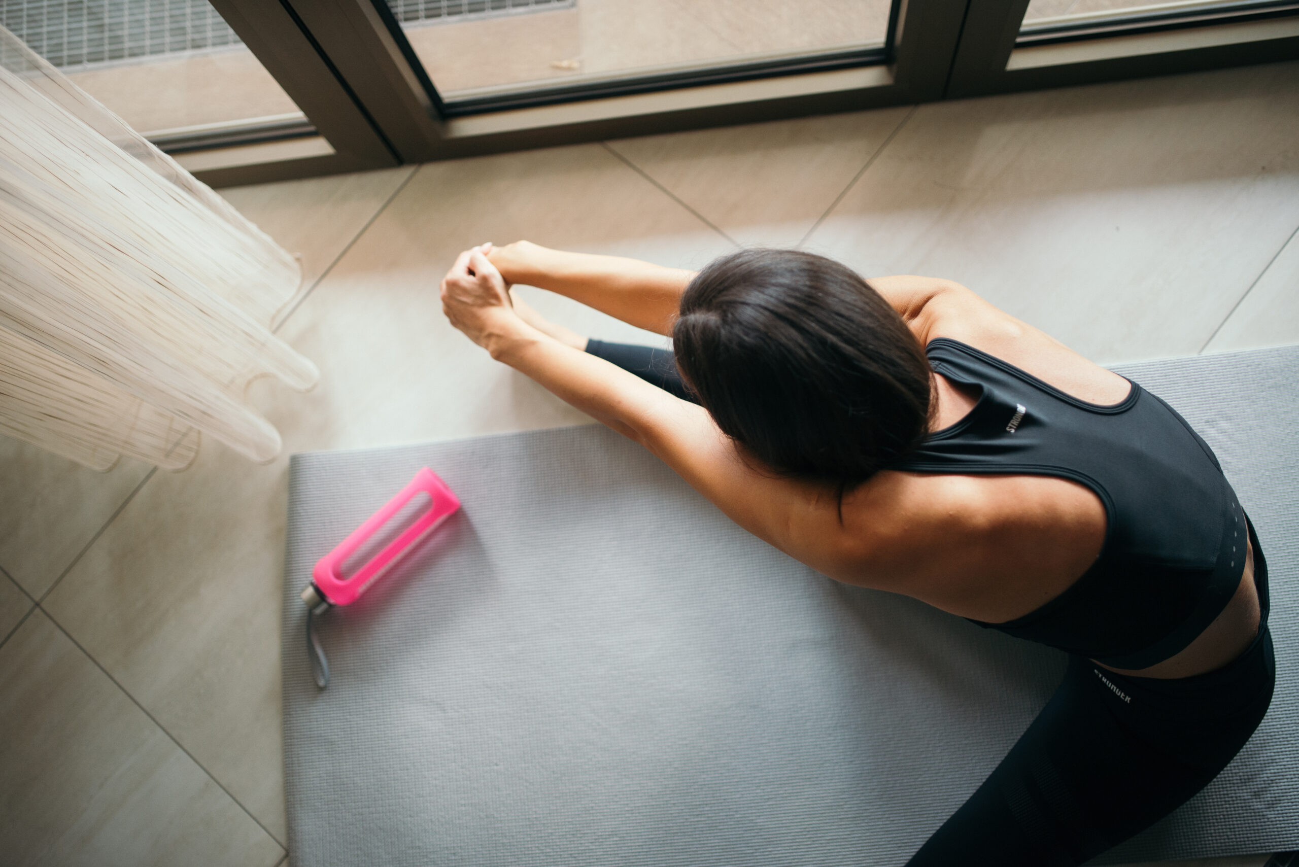 Femme vue de dessus réalisant un étirement doux sur un tapis